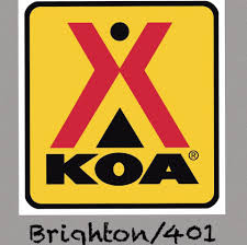 KOA campground logo with a red "X" and black triangle above the text "KOA" on a yellow background; "Brighton/401" written below.
