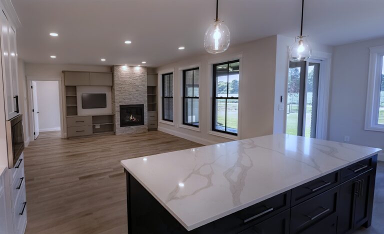 Modern open-concept living space with a marble kitchen island, dark cabinetry, pendant lights, and large windows—perfect for Bay of Quinte entrepreneurs seeking a cozy living area with a stone fireplace and stylish built-in shelving.